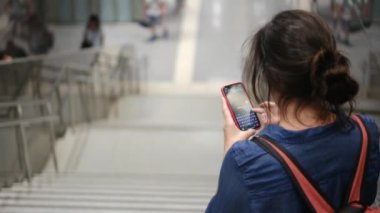 Metro istasyonunda akıllı telefon kullanan genç bir kadın. 