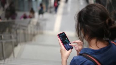Metro istasyonunda akıllı telefon kullanan genç bir kadın. 