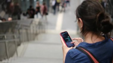 Metro istasyonunda akıllı telefon kullanan genç bir kadın. 