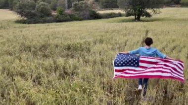 Amerika bayrağıyla sahada koşan bir kadının arka plan görüntüsü. 4 Temmuz Bağımsızlık Günü.