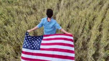 Amerika bayrağıyla sahada koşan bir kadının arka plan görüntüsü. 4 Temmuz Bağımsızlık Günü.