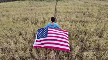 Amerika bayrağıyla sahada koşan bir kadının arka plan görüntüsü. 4 Temmuz Bağımsızlık Günü.