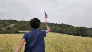 Amerika bayrağı elinde koşan bir çocuğun arka görüntüsü. 4 Temmuz Bağımsızlık Günü.