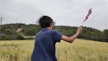 Amerika bayrağı elinde koşan bir çocuğun arka görüntüsü. 4 Temmuz Bağımsızlık Günü.