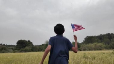 Amerika bayrağı elinde koşan bir çocuğun arka görüntüsü. 4 Temmuz Bağımsızlık Günü.