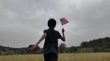 Amerika bayrağı elinde koşan bir çocuğun arka görüntüsü. 4 Temmuz Bağımsızlık Günü.