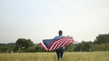 ABD bayraklı bir kadının tarlada yürüyüşü. 4 Temmuz Bağımsızlık Günü.