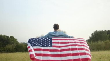 ABD bayraklı bir kadının tarlada yürüyüşü. 4 Temmuz Bağımsızlık Günü.