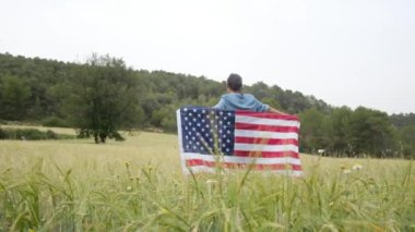 Sahada ABD bayrağı olan bir kadının arka görüntüsü. 4 Temmuz Bağımsızlık Günü.