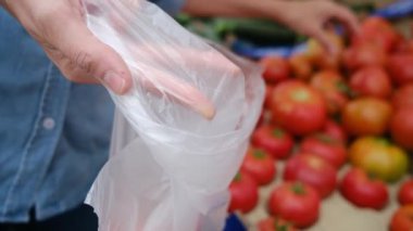 Kadın elinde torbayla domatesleri pazara sürüyor.