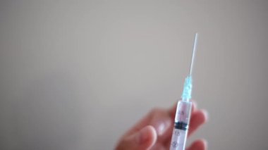 Kadın eli şırıngayı tutuyor, yakın plan.