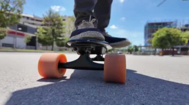 Kaykaycının ayakları şehrin caddesinde Mini Longboard kruvazörüyle kaykay yapıyor. 