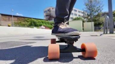 Kaykaycının ayakları şehrin caddesinde Mini Longboard kruvazörüyle kaykay yapıyor. 