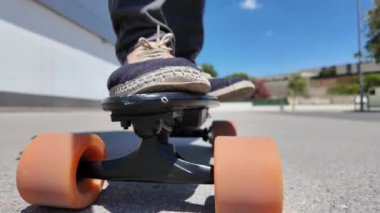 Kaykaycının ayakları şehrin caddesinde Mini Longboard kruvazörüyle kaykay yapıyor. 