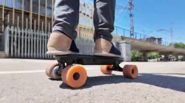 Kaykaycının ayakları şehrin caddesinde Mini Longboard kruvazörüyle kaykay yapıyor. 