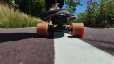 Kaykaycının ayakları şehrin caddesinde Mini Longboard kruvazörüyle kaykay yapıyor. 