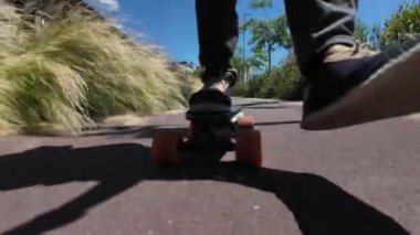 Kaykaycının ayakları şehrin caddesinde Mini Longboard kruvazörüyle kaykay yapıyor. 