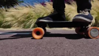 Kaykaycının ayakları şehrin caddesinde Mini Longboard kruvazörüyle kaykay yapıyor. 