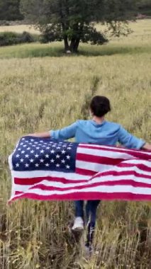 Amerika bayrağıyla sahada koşan bir kadının arka plan görüntüsü. 4 Temmuz Bağımsızlık Günü.