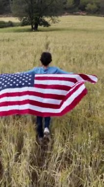 Amerika bayrağıyla sahada koşan bir kadının arka plan görüntüsü. 4 Temmuz Bağımsızlık Günü.