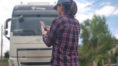 Arkasında kamyonet olan akıllı telefon kullanan genç bir kadın. 