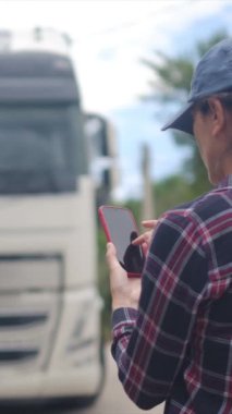 Arkasında kamyonet olan akıllı telefon kullanan genç bir kadın. 