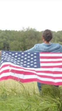 Sahada ABD bayrağı olan bir kadının arka görüntüsü. 4 Temmuz Bağımsızlık Günü.