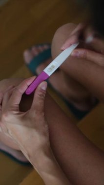 Hamilelik testi olan genç bir kadın, sonuçları kontrol ediyor, sabahları evde oturuyor. Hamilelik, sağlık