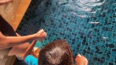 baba, anne ve çocuk havuza atlayıp top güllesi yapıyorlar, yaz tatili 8 yaşındaki çocuklar için eğlenceli. Su sporları ve sağlıklı yaşam ile açık havada aktif yaşam tarzı