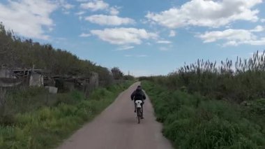 Sıcak ve güneşli bir günde bisiklet süren bir adam.