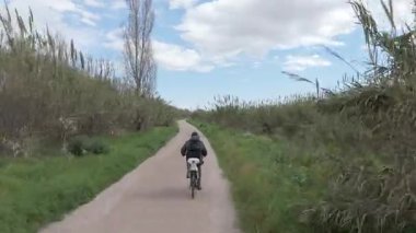 Sıcak ve güneşli bir günde bisiklet süren bir adam.