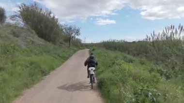 Sıcak ve güneşli bir günde bisiklet süren bir adam.