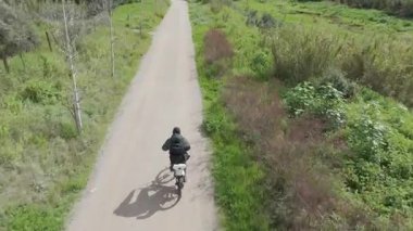 Sıcak ve güneşli bir günde bisiklet süren bir adam.