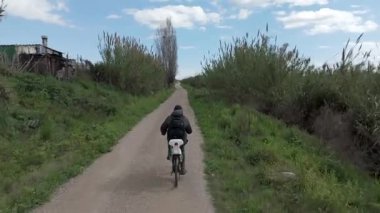 Genç adam güneşli bir günde bisiklet sürüyor.