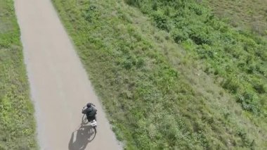 Sıcak ve güneşli bir günde bisiklet süren bir adam.