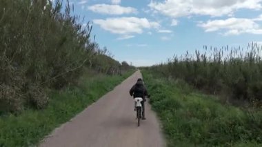 Sıcak ve güneşli bir günde bisiklet süren bir adam.