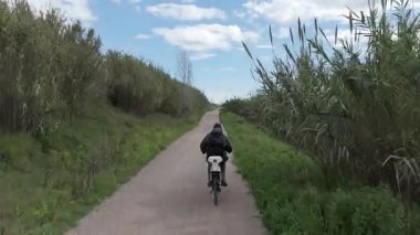 Sıcak ve güneşli bir günde bisiklet süren bir adam.