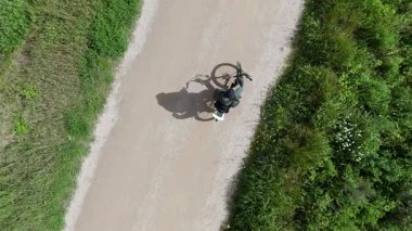 Akıllı telefonlu bisikletli bir adam güneşli bir günde yol bulmaya çalışıyor.