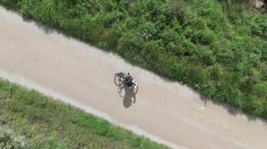 Akıllı telefonlu bisikletli bir adam güneşli bir günde yol bulmaya çalışıyor.