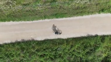 Akıllı telefonlu bisikletli bir adam güneşli bir günde yol bulmaya çalışıyor.