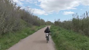 Sıcak ve güneşli bir günde bisiklet süren bir adam.