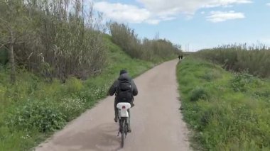 Sıcak ve güneşli bir günde bisiklet süren bir adam.