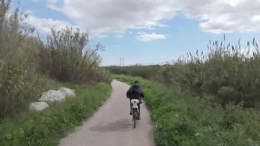 Sıcak ve güneşli bir günde bisiklet süren bir adam.