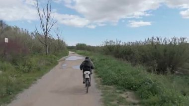 Genç adam güneşli bir günde bisiklet sürüyor.