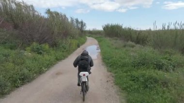 Genç adam güneşli bir günde bisiklet sürüyor.