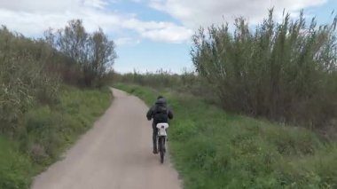 Genç adam güneşli bir günde bisiklet sürüyor.