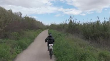 Genç adam güneşli bir günde bisiklet sürüyor.