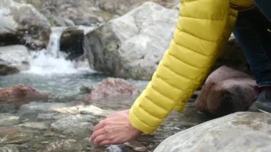 Dağlarda kış mevsimi. Soğuk nehir suyunda ellerini yıkayan kadın videosu. 