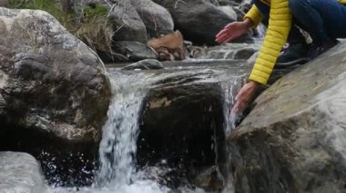 Elleri soğuk nehir buharlı suyunda yıkayan kadın videosu. Dağlarda kış mevsimi 