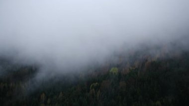 Bulutlu havada sisli dağların manzarasını gösteren drone videosu. Soğuk hava 